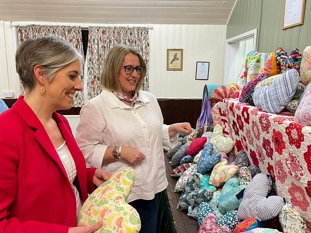 Daisy Cooper MP and Heather Hunt from the Mead Quilters group look at the quilts and cushions they will donate to charity