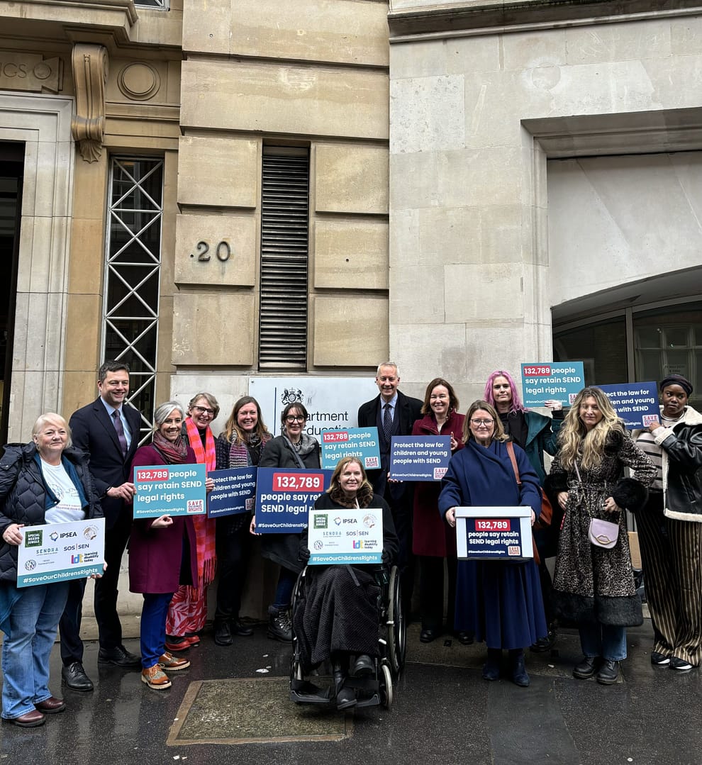 A group of campaigners and MPs are standing in front of the Department for Education. Many of them are holding signs, including Daisy, who is holding a sign saying '132,789 people say retain SEND legal rights'.